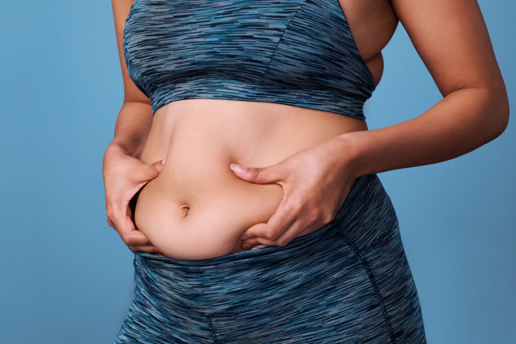 Woman in workout clothes holding bloated stomach