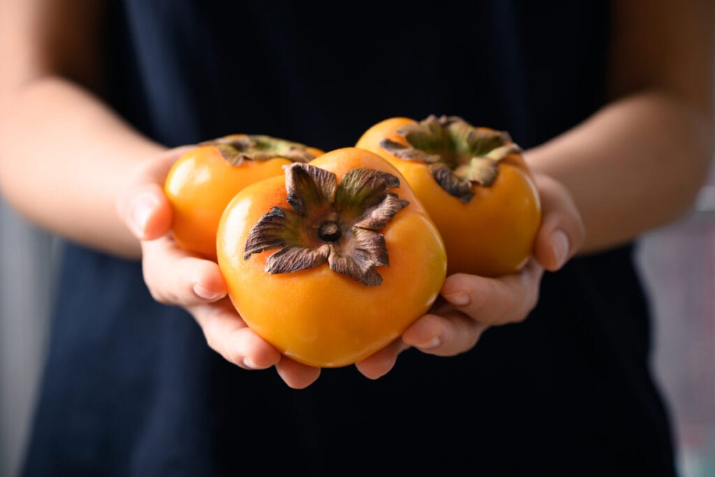 Close up of woman holding persimmons