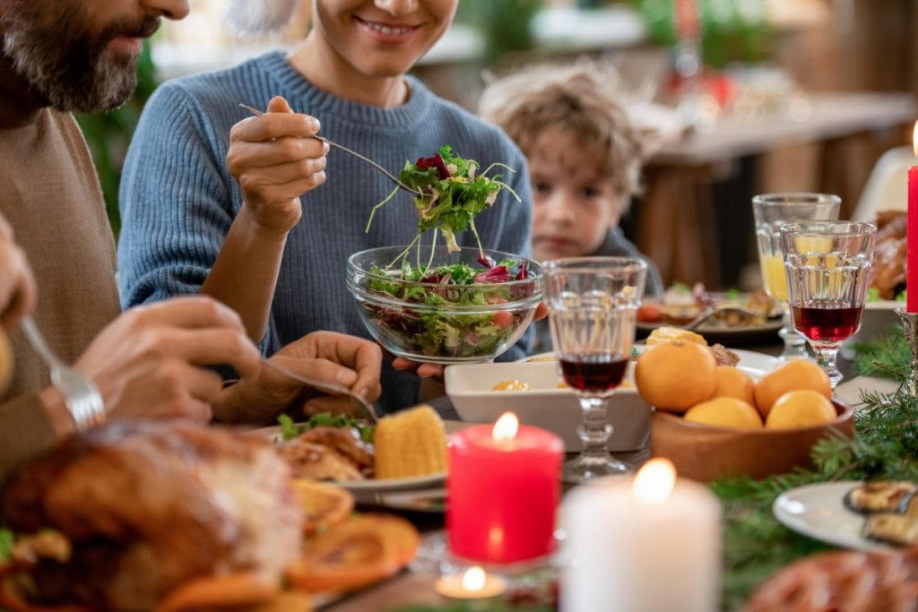 Woman eating a leafy green salad during a holiday dinner