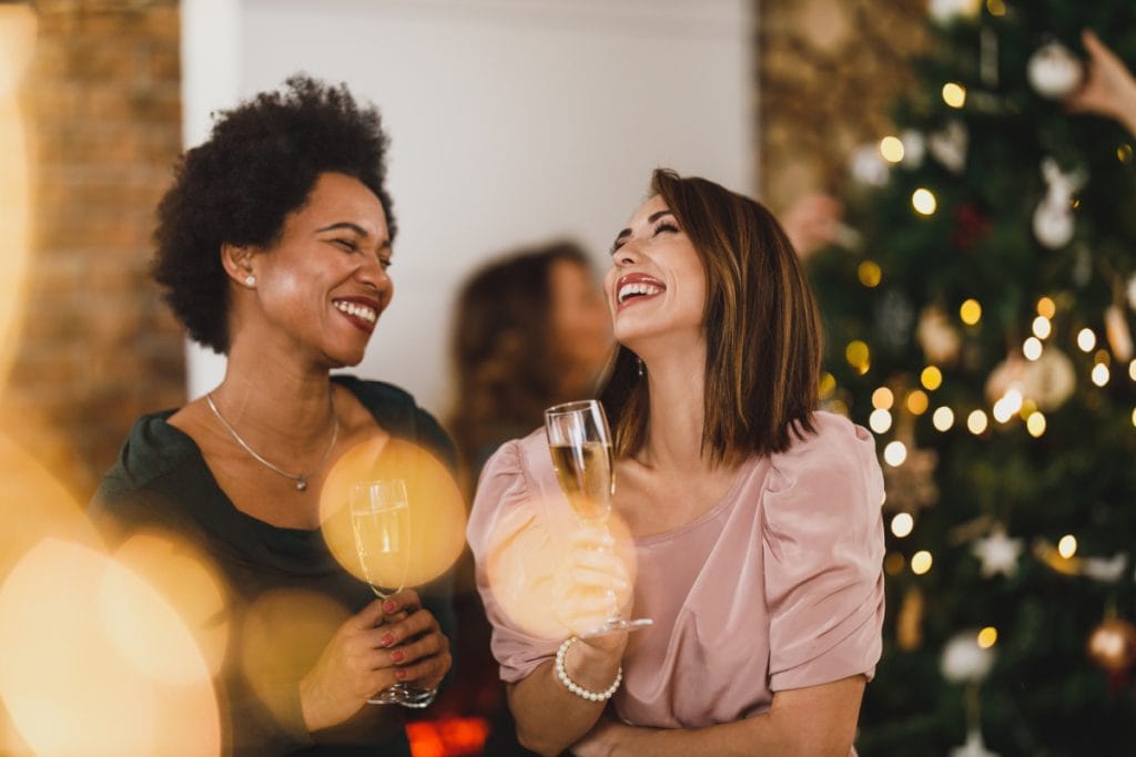 Two women drinking champagne at a holiday party