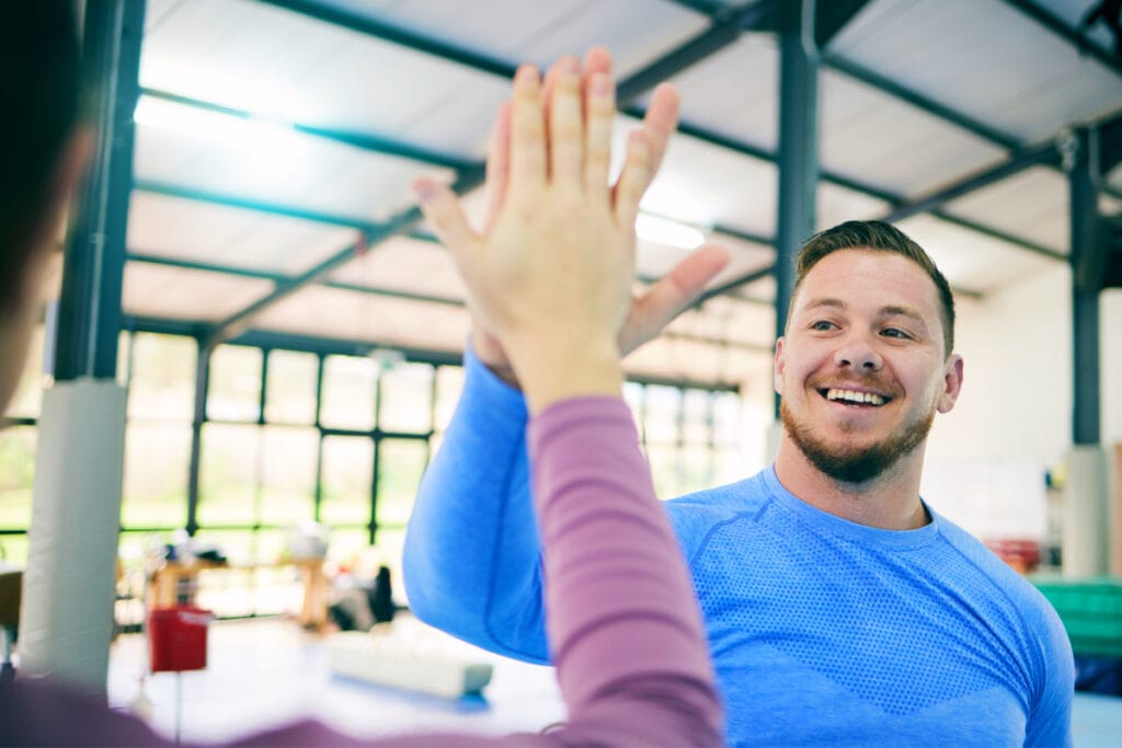 Man high fiving partner at gym after workout